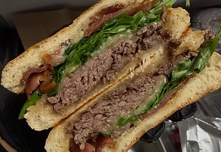 Large stacked breakfast sandwich held in the kitchen