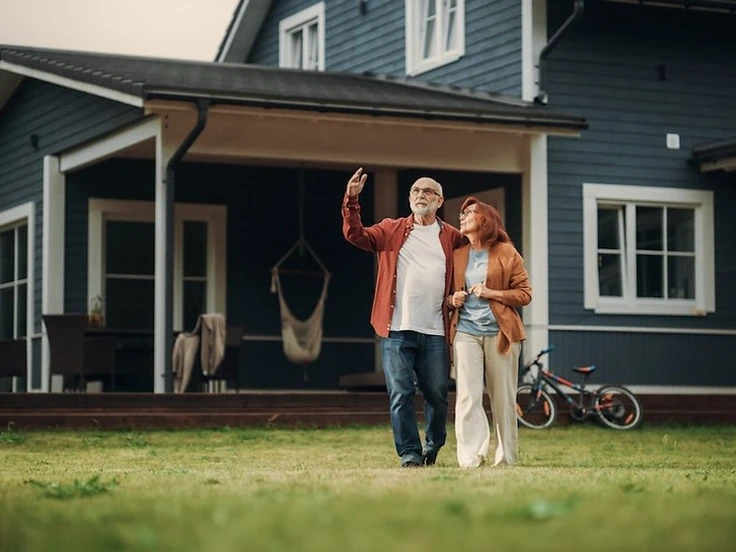An older couple standing together outside their home