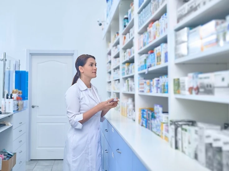 A pharmacist reviewing medication on a pharmacy shelf
