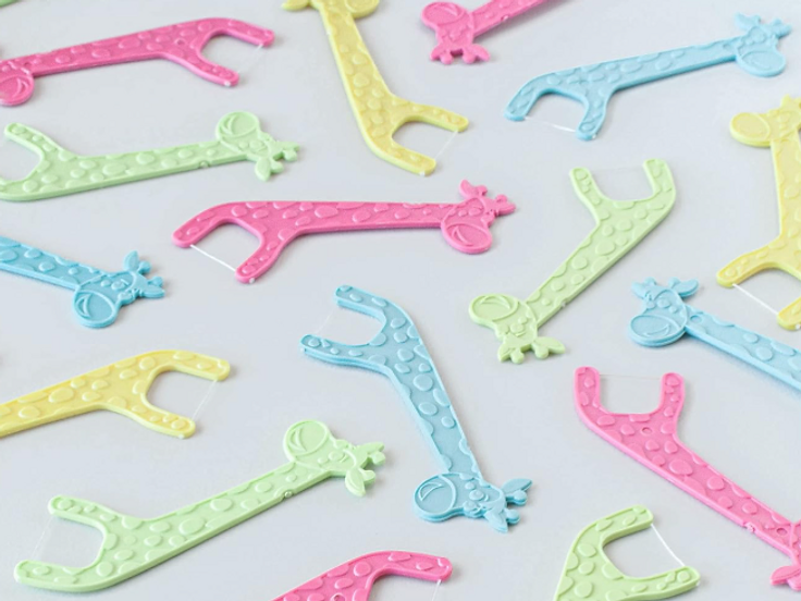 Colorful giraffe-shaped kids floss picks scattered