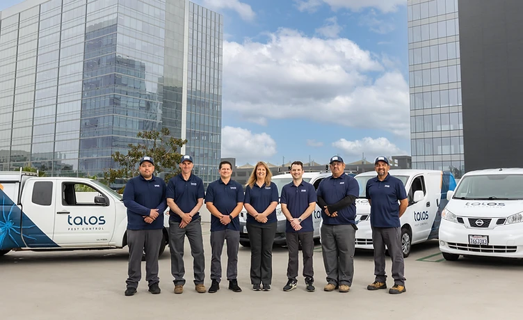 The Talos Pest Control team — field technicians and office staff in uniform with Talos service vans