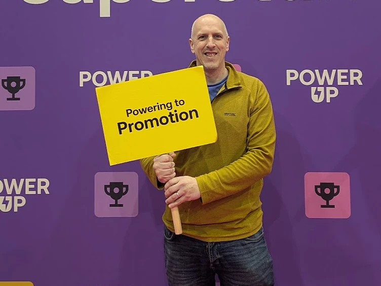 Martin holding a Powering to Promotion sign