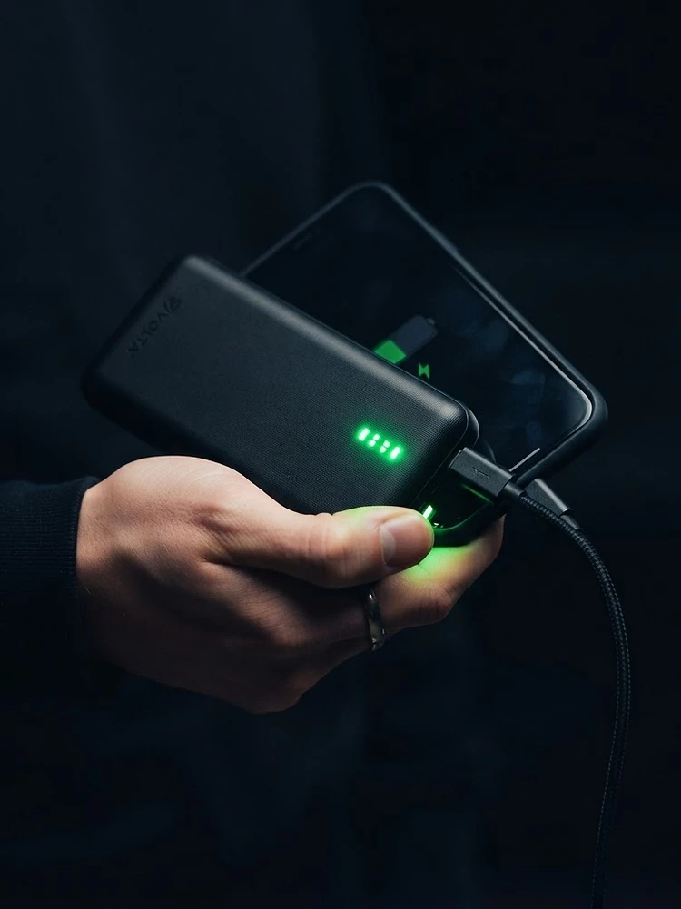 A hand charging a phone with a Rapid power bank