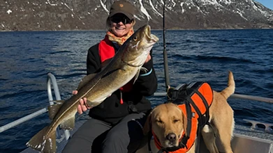 Guest holding a freshly caught cod on the fishing boat at Ersfjordbotn Brygge