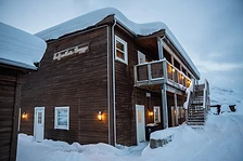 Snow-covered Ersfjordbotn Brygge apartment building at twilight with warm exterior lights