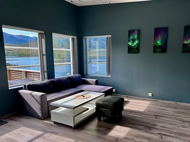 Modern Scandinavian living room with floor-to-ceiling windows overlooking the fjord at Ersfjordbotn Brygge