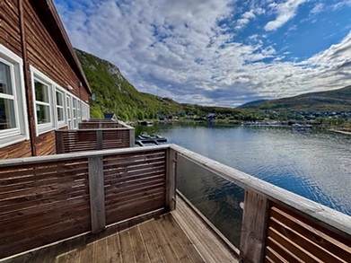 Wooden balcony overlooking the fjord and mountains from a fjordside apartment at Ersfjordbotn Brygge