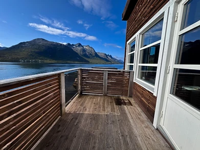 Outdoor deck view over the fjord and snowy peaks from Ersfjordbotn Brygge