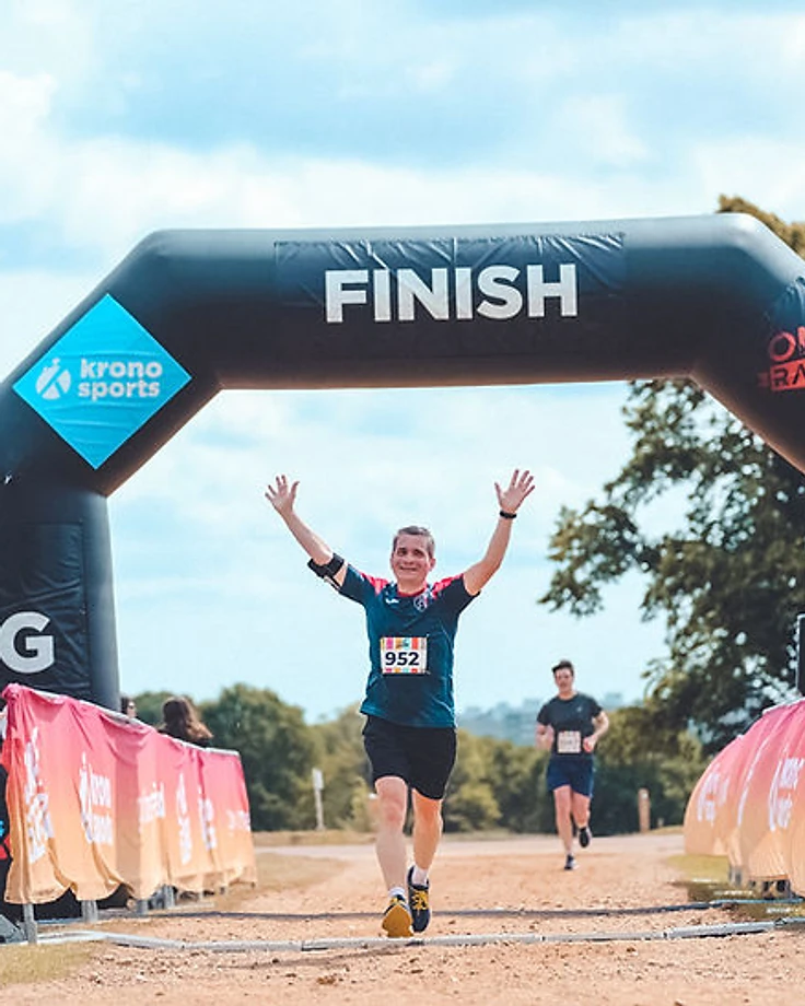 Runner celebrating at a OneRace finish arch