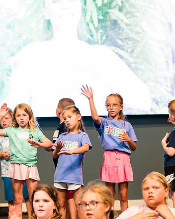 Children sing with hand motions during a kids worship service