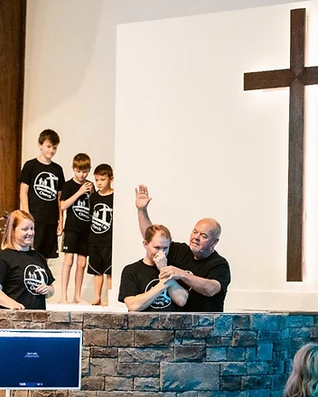 The church family gathers to pray over a man before his baptism