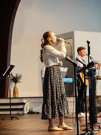 A young woman sings on the worship team during a Sunday service