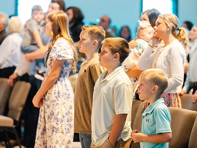 Children and families stand together during a Sunday worship service