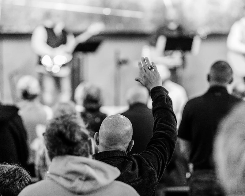 A hand raised in worship as the band leads a song at Abundant Life Church