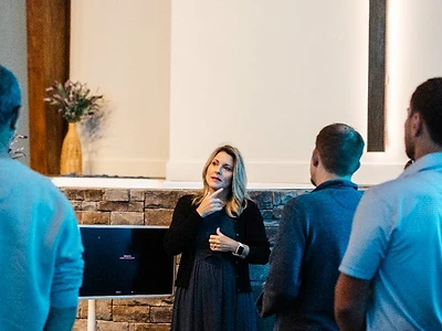 A woman shares a teaching in front of the lighted cross in the sanctuary
