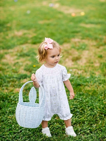 A little girl carries a bunny basket across the lawn at the Easter egg hunt