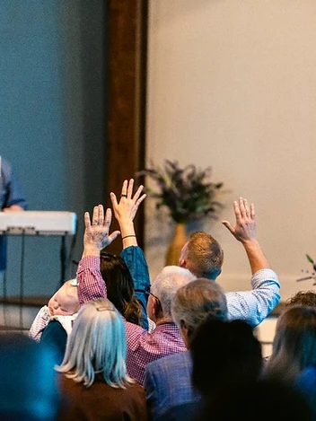 Hands raised in worship as the pianist leads the congregation in song