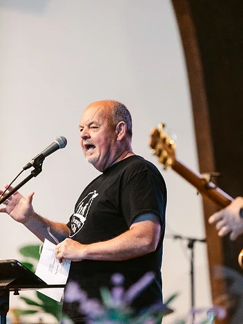 A man speaks passionately at the microphone during a church gathering