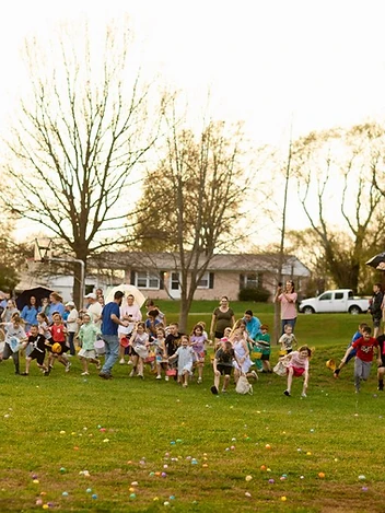 Families spread across the lawn hunting Easter eggs together