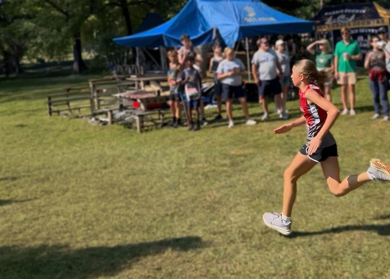 Cherokee Junior Warriors runner mid-stride at a cross-country race