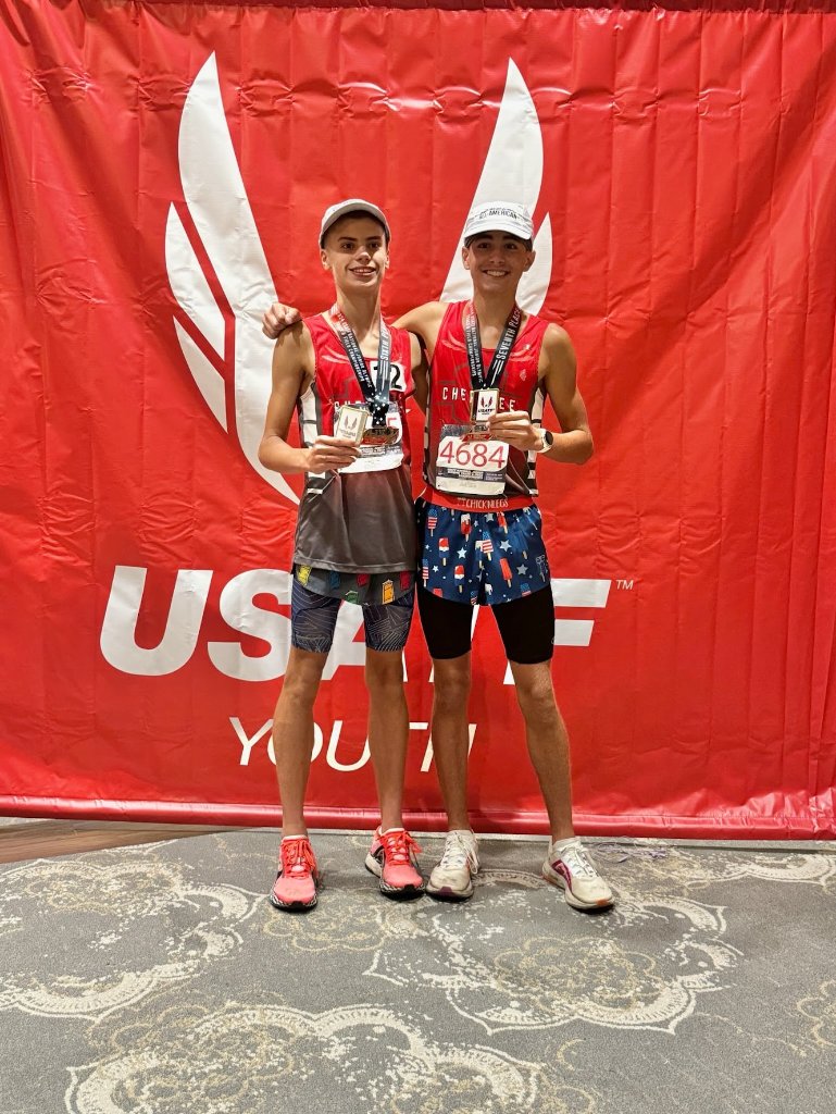 Two Cherokee athletes showing off their medals at a USATF event