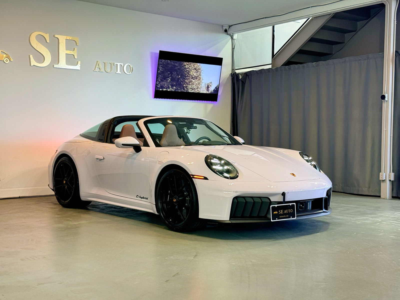 White Porsche 911 Targa 4 GTS, three-quarter front view, in a dealer’s showroom.