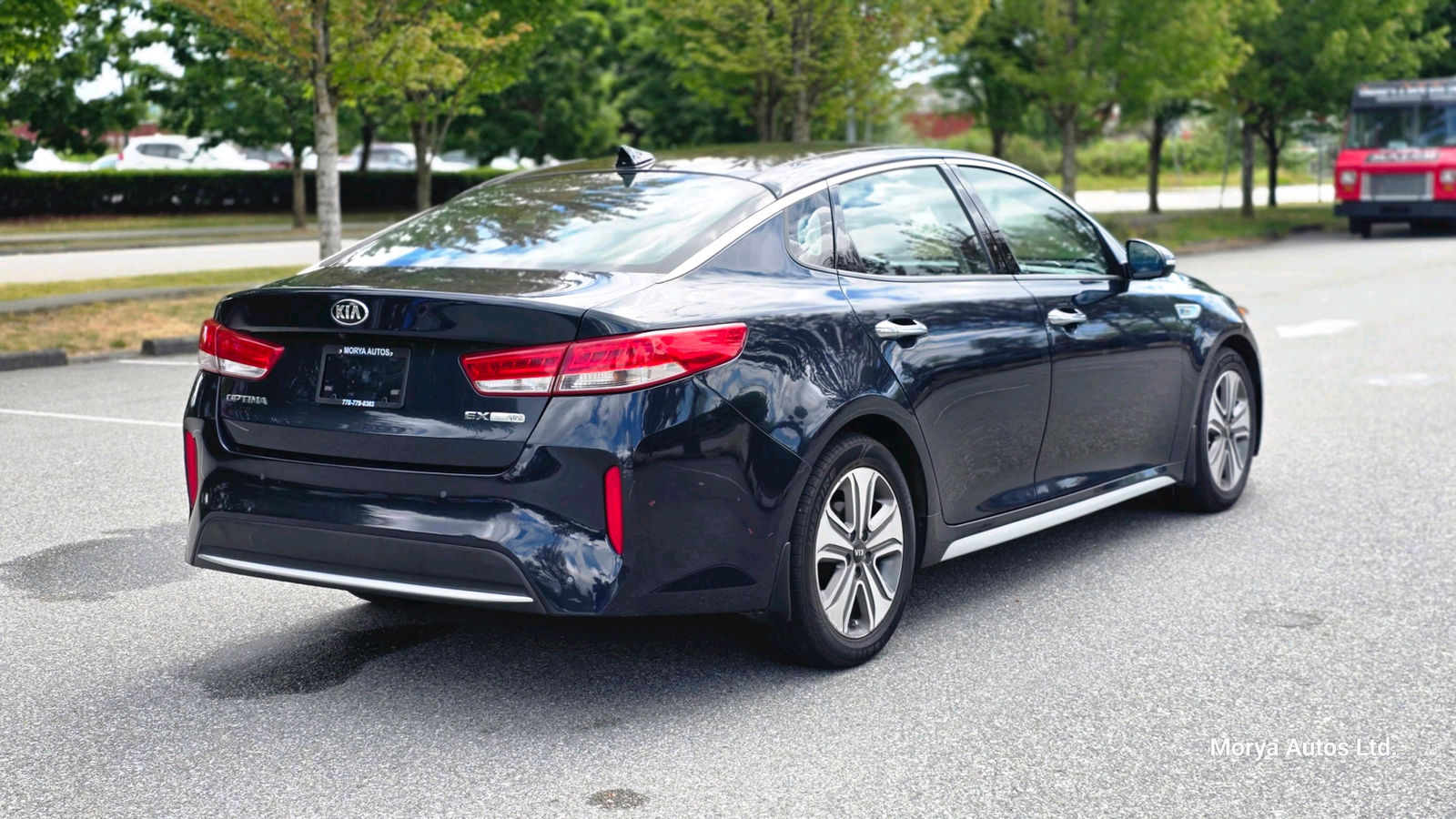 2017 Kia Optima in dark blue, rear three-quarter view from the driver side, on a dealer’s lot.
