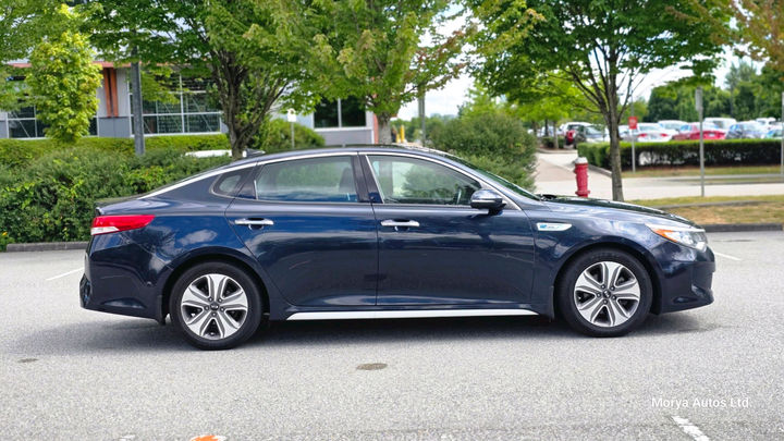 2017 Kia Optima in dark blue, driver-side profile, on a dealer’s lot.