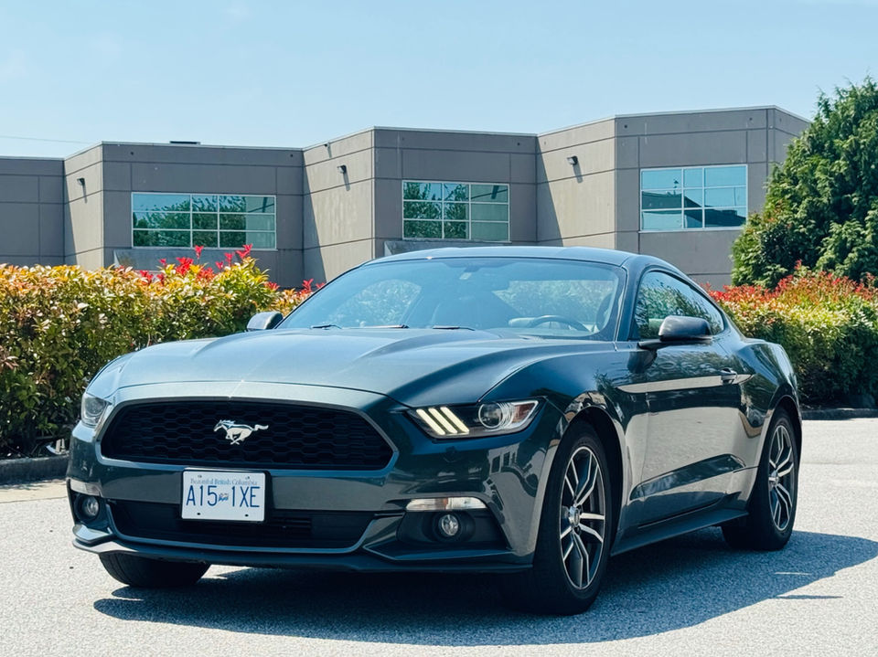Dark green 2015 Ford Mustang EcoBoost, three-quarter front view, on a dealership lot.