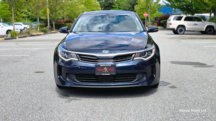2017 Kia Optima in dark blue, straight-on front view, on a dealer’s lot.