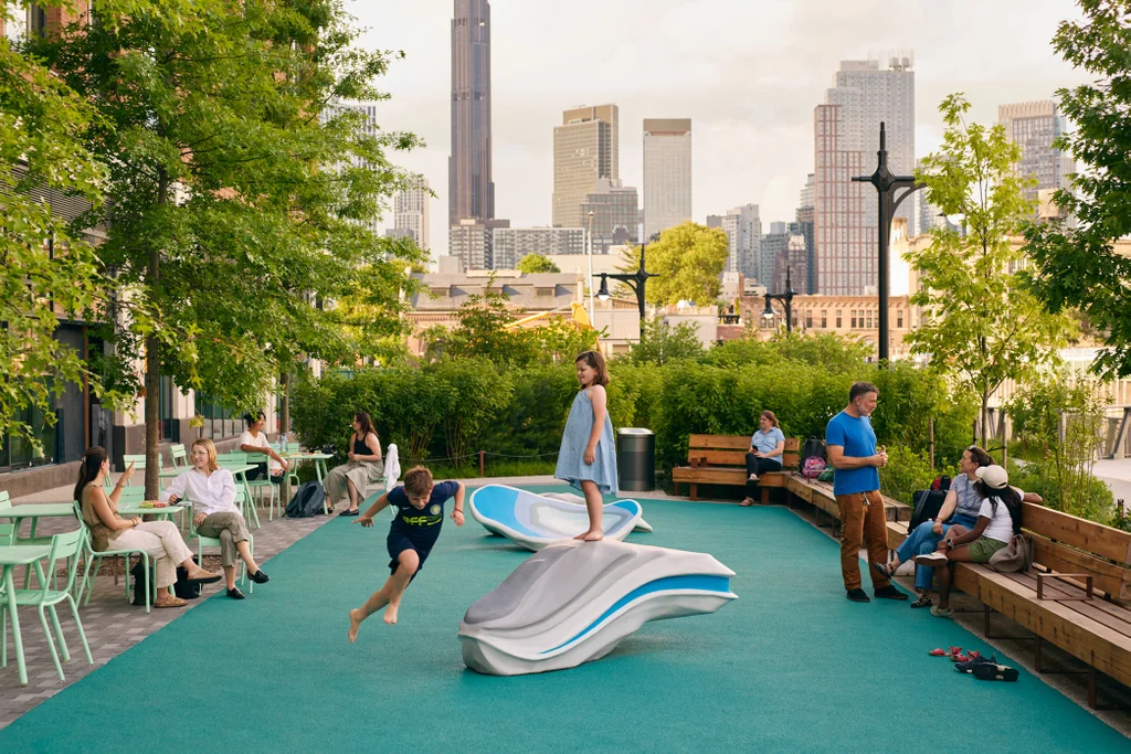 Families gathered in a Brooklyn residence courtyard with the city skyline beyond