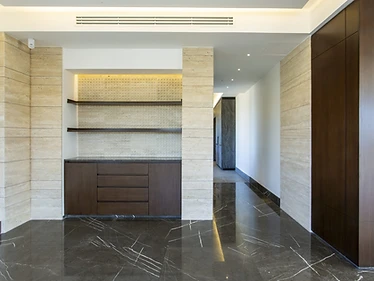 Coffee niche as built, duplex interior design, Amman: travertine columns, walnut drawers, dark marble floor