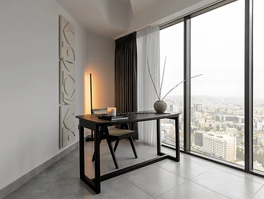 Desk nook, flat interior design, Amman: black steel desk, cane-back chair, carved stone wall panel