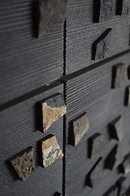 Basalt wall art detail, flat interior design, Amman: close-up of ribbed texture and raw stone chips
