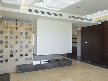 Living area as built, duplex interior design, Amman: breeze-block screen and dark marble bench on cream marble