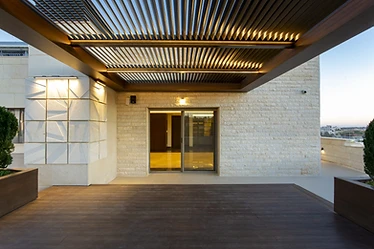 Under the pergola, roof terrace design, Amman: lit louvres above a wood deck facing the glass doors