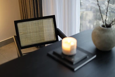 Desk vignette, flat interior design, Amman: lit candle, textured ceramic vase, cane-back chair