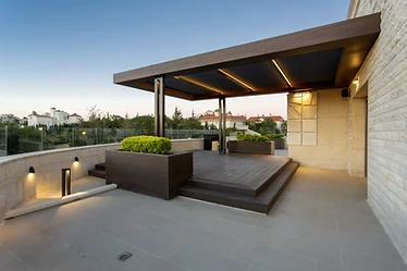 Roof terrace design, Amman: lit steel and wood pergola over a raised deck and planters at dusk