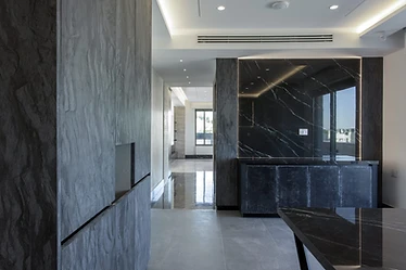 Kitchen and dining, duplex interior design, Amman: dark veined marble wall beside a textured stone column