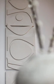 Limestone wall art detail, flat interior design, Amman: carved arc motif beside a dried branch arrangement