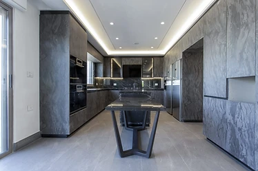 Kitchen, duplex interior design, Amman: dark marble cladding, built-in ovens and an island table