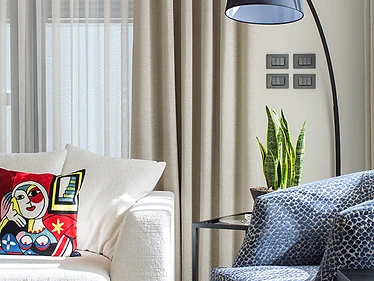 P.A Residence in Manama featuring a bright sitting area with collected artwork, patterned blue chairs and colorful decorative cushions