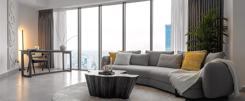 Living room, flat interior design, Amman: curved grey sofa, black sculptural coffee table, floor-to-ceiling city view