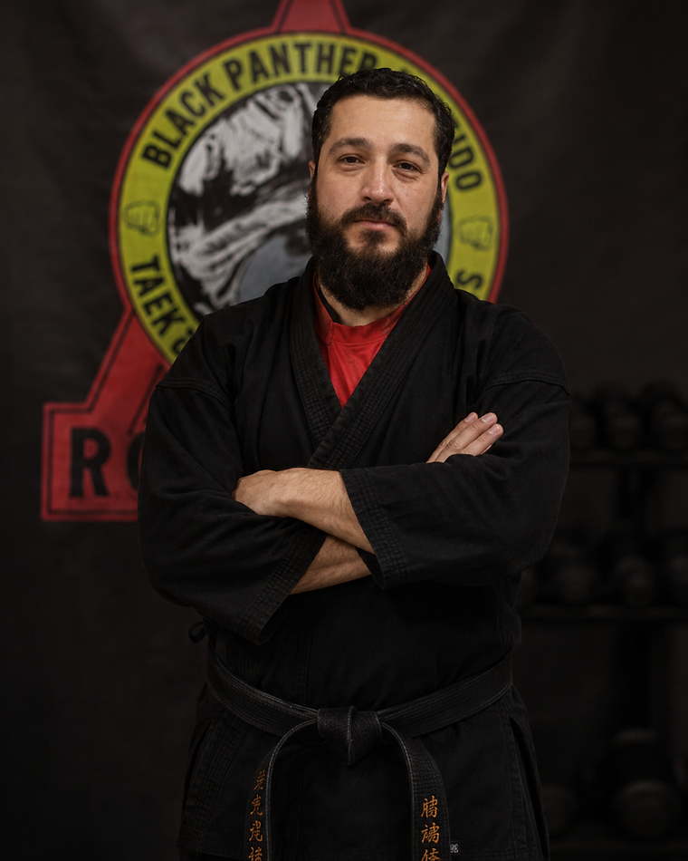 Black and white portrait of Master Rolando Moreno in a black martial arts uniform