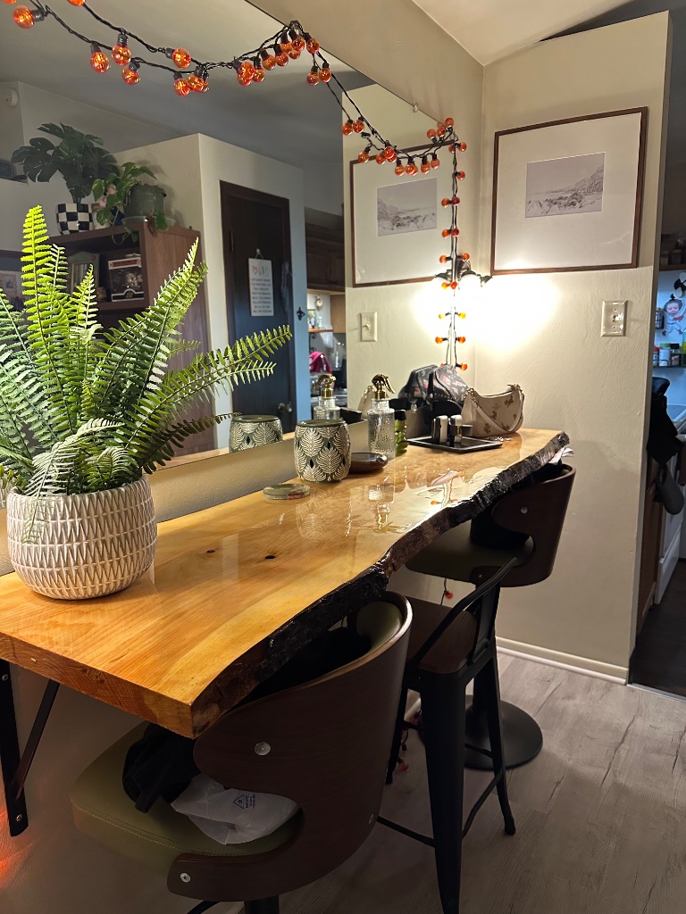 Live-edge wood bar counter with fern and warm fairy lights