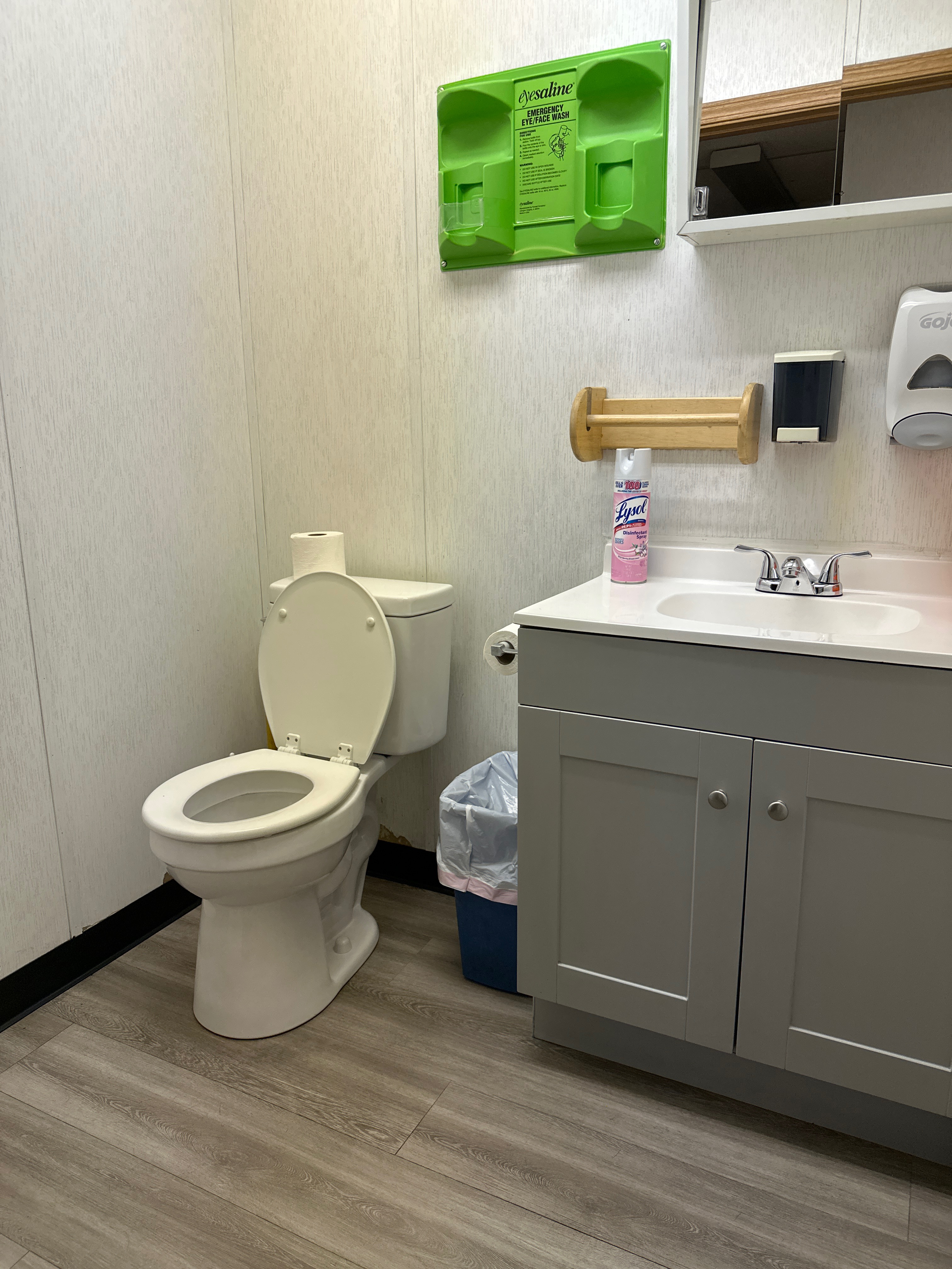 Clean commercial restroom with vanity, toilet, and eye wash station