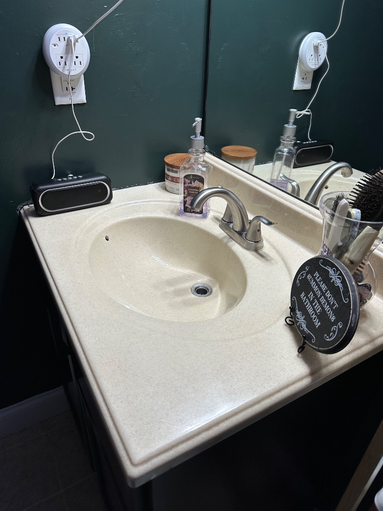 Bathroom vanity with green wall and organized accessories