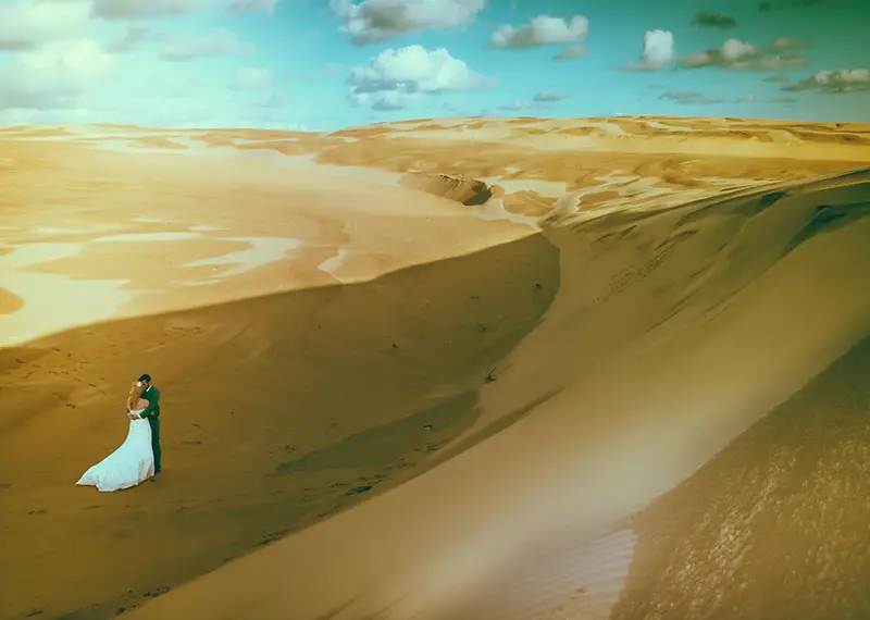 Tina and Stephen walking along the sandy beach during their beautiful Newcastle wedding in Anna Bay