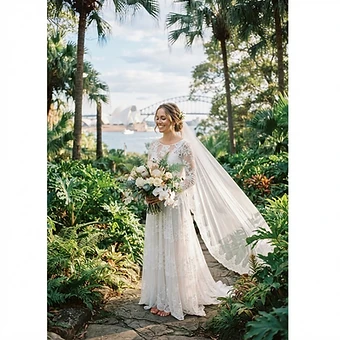 Sydney wedding photography — a bride in a white lace dress with a flowing veil among lush palms and foliage in the Royal Botanic Garden Sydney
