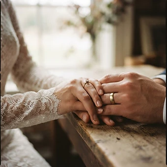 Sydney wedding photography — close-up of a bride and groom’s joined hands showing wedding rings in soft window light